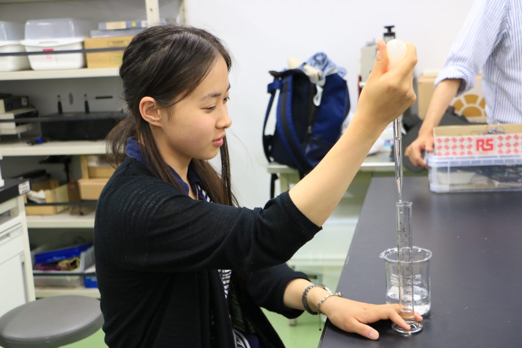スポイトで試験管に実験用水を入れている学生