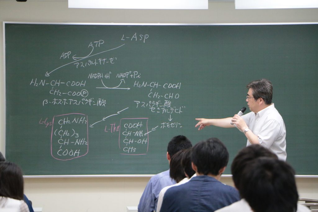 黒板に書いた阻害要因について説明する片岡先生の写真