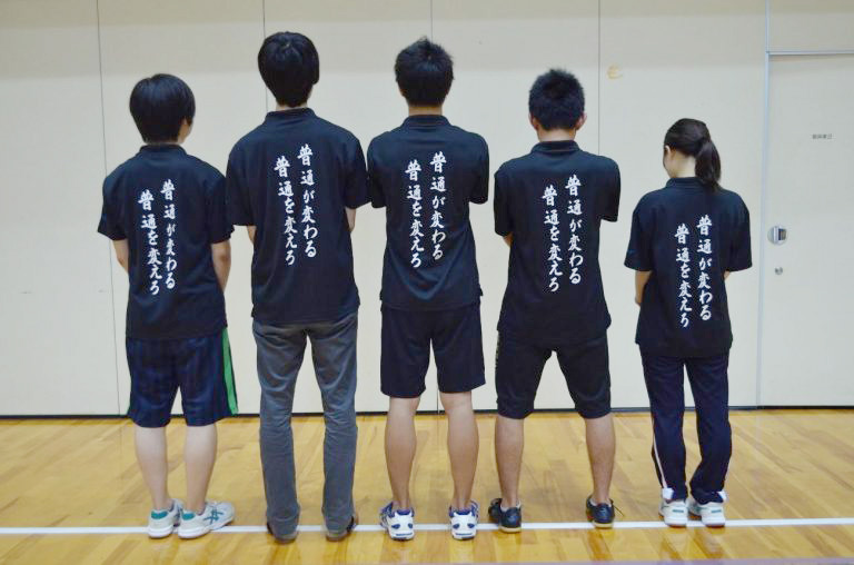 「普通が変わる普通を変えろ」の文字が掛かれたTシャツを着ている部員の写真